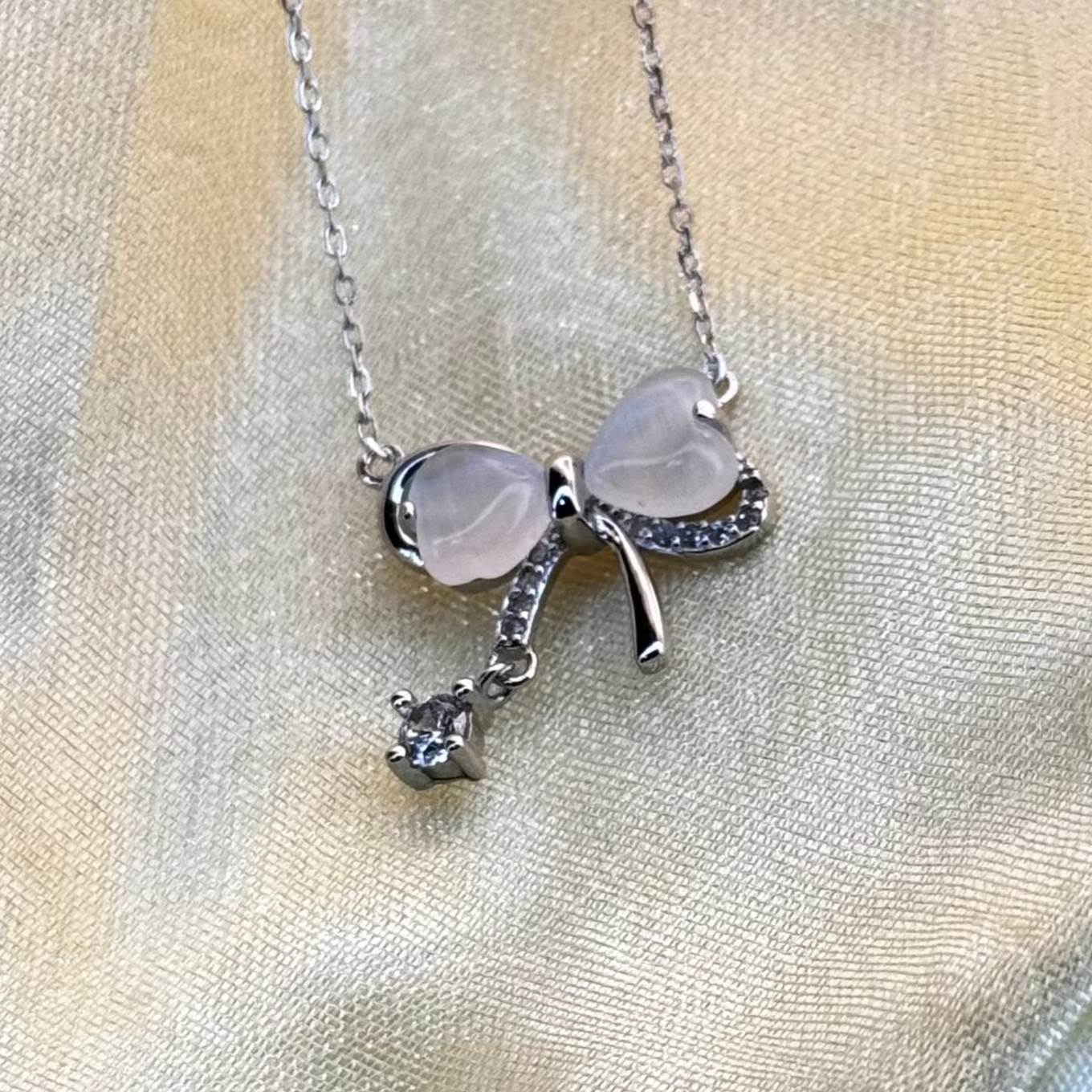 Necklace with a bow-shaped pendant on a light fabric background
