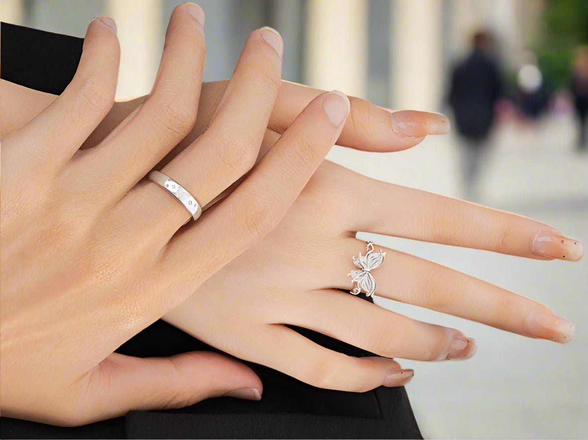 Close-up of a hand wearing two silver rings with a plain background