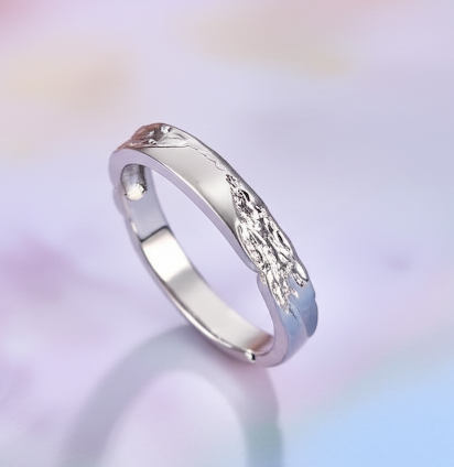 Silver ring with intricate design on a soft, multicolored background